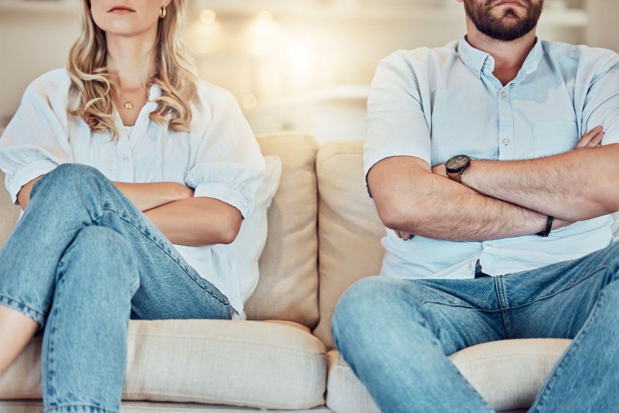 Paar mit verschraenkten Armen auf Sofa als Darstellung fuer Konflikt vor dem Scheidungsantrag