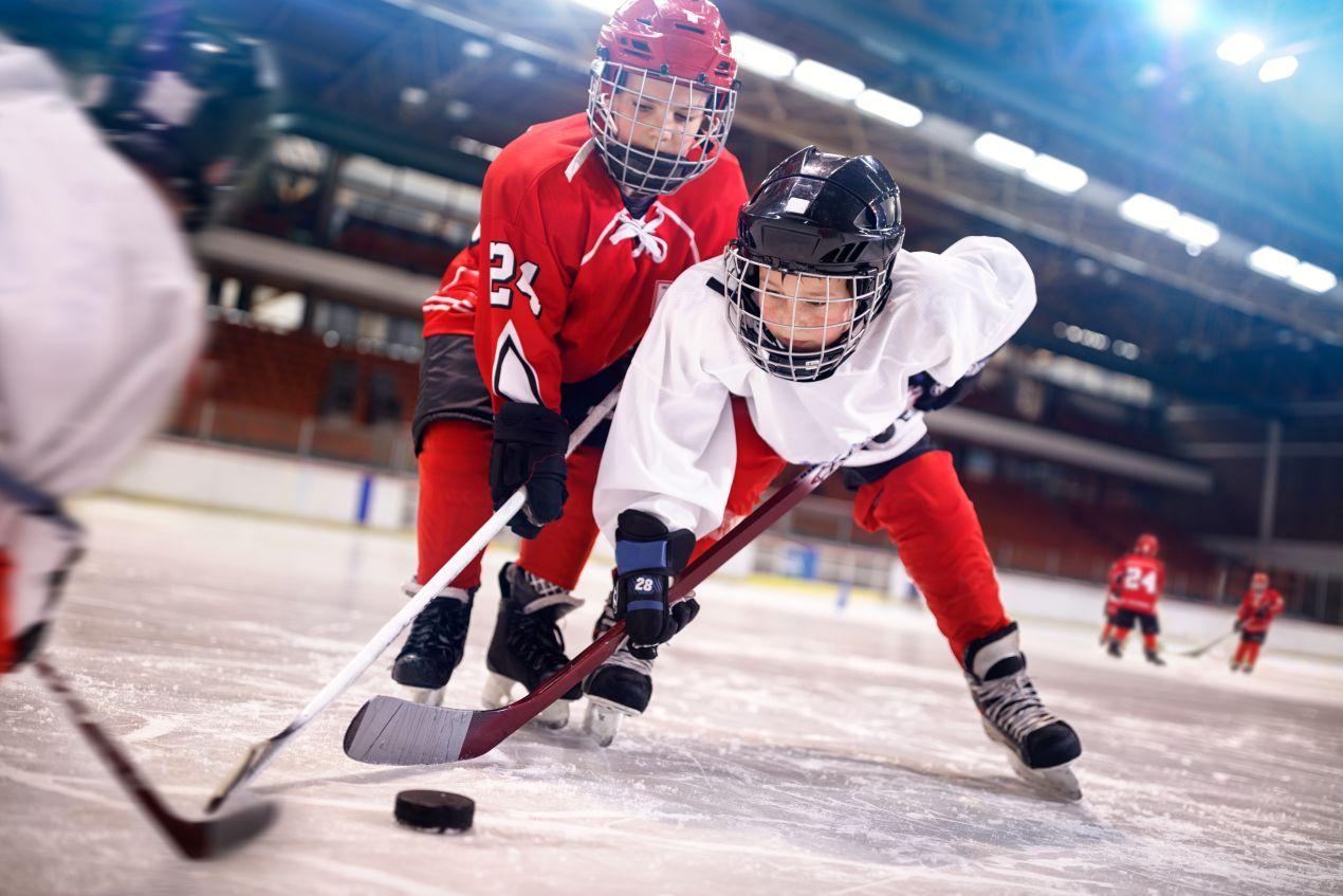 Zwei junge Eishockeyspieler kaempfen um den Puck auf dem Eis – Bauer Eishockey Ausruestung im Jugendbereich
