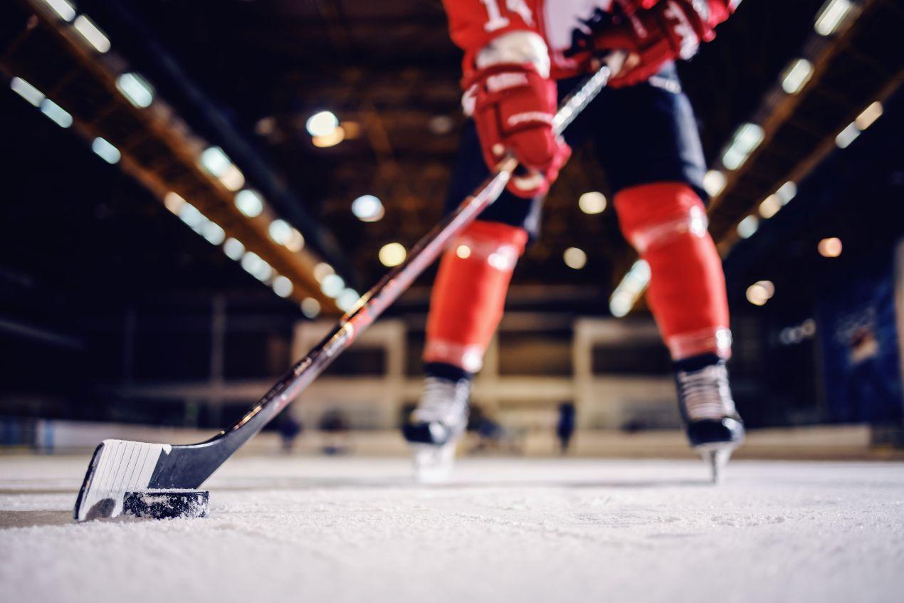 Detailaufnahme eines Eishockeyspielers beim Stickhandling mit Schlaeger und Puck – Bauer Eishockey Equipment auf dem Eis