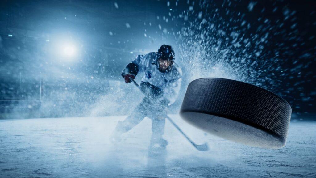 Eishockeyspieler beim Schlagschuss in voller Action mit fliegendem Puck – Bauer Eishockey Ausruestung im Einsatz