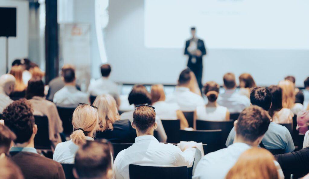 Teilnehmer sitzen in einem Konferenzraum und folgen einer Praesentation – typisches Beispiel fuer Eventlocations NRW im Business-Bereich